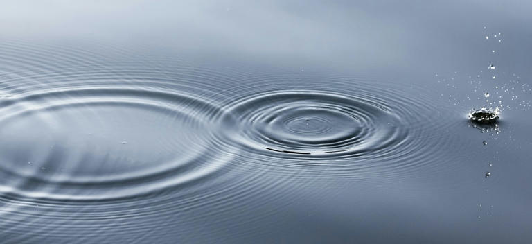 Picture of a drip of water causing ripples in a larger body of water